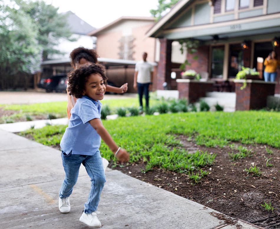 Happy child running outside in front of family home