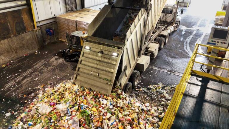 Garbage truck unloading waste at recycling facility indoors