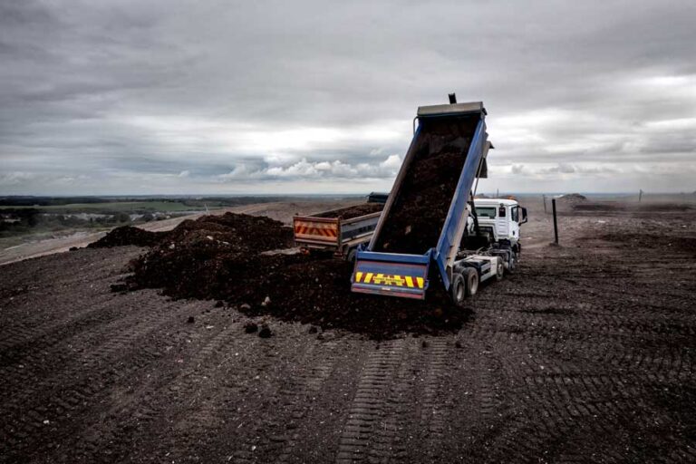 Dump truck unloading waste at facility